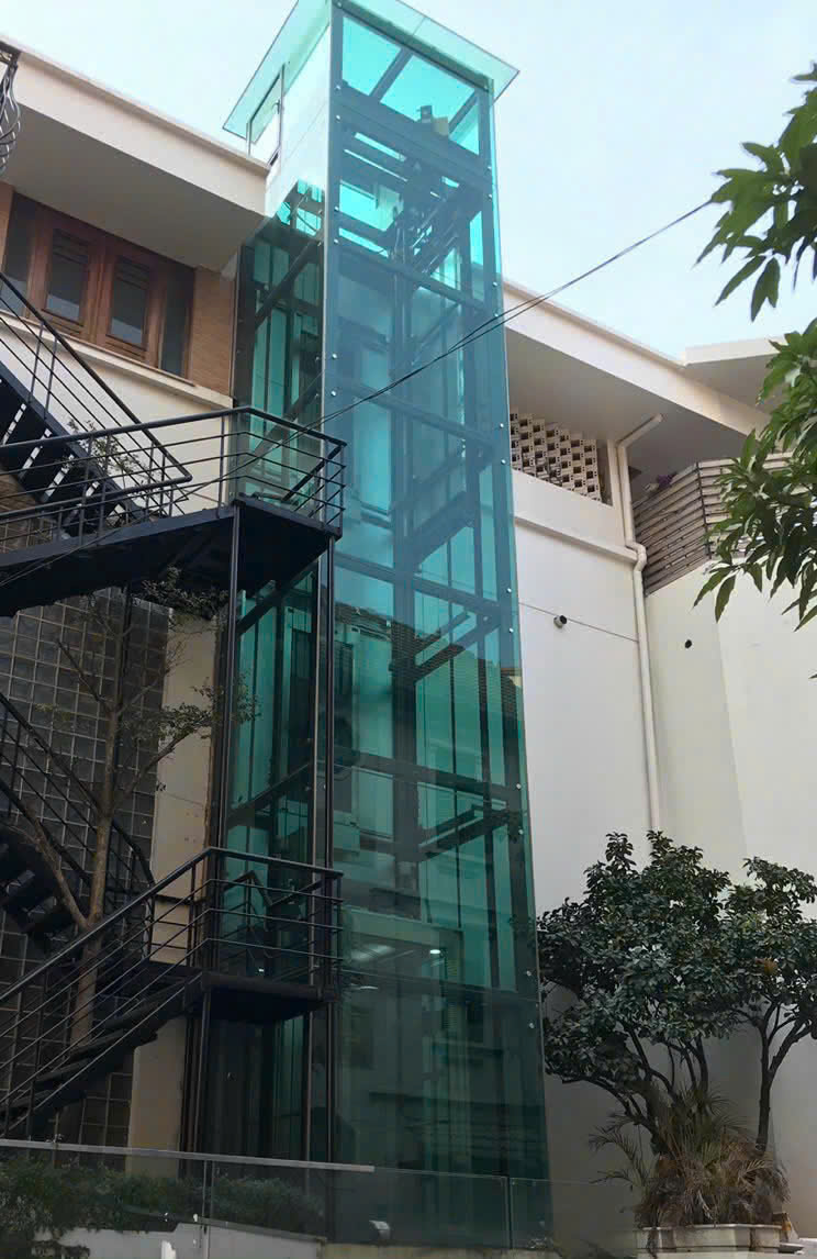 Thang máy kính ngoài trời lắp đặt bên hông nhà nhiều tầng với khung thép hiện đại